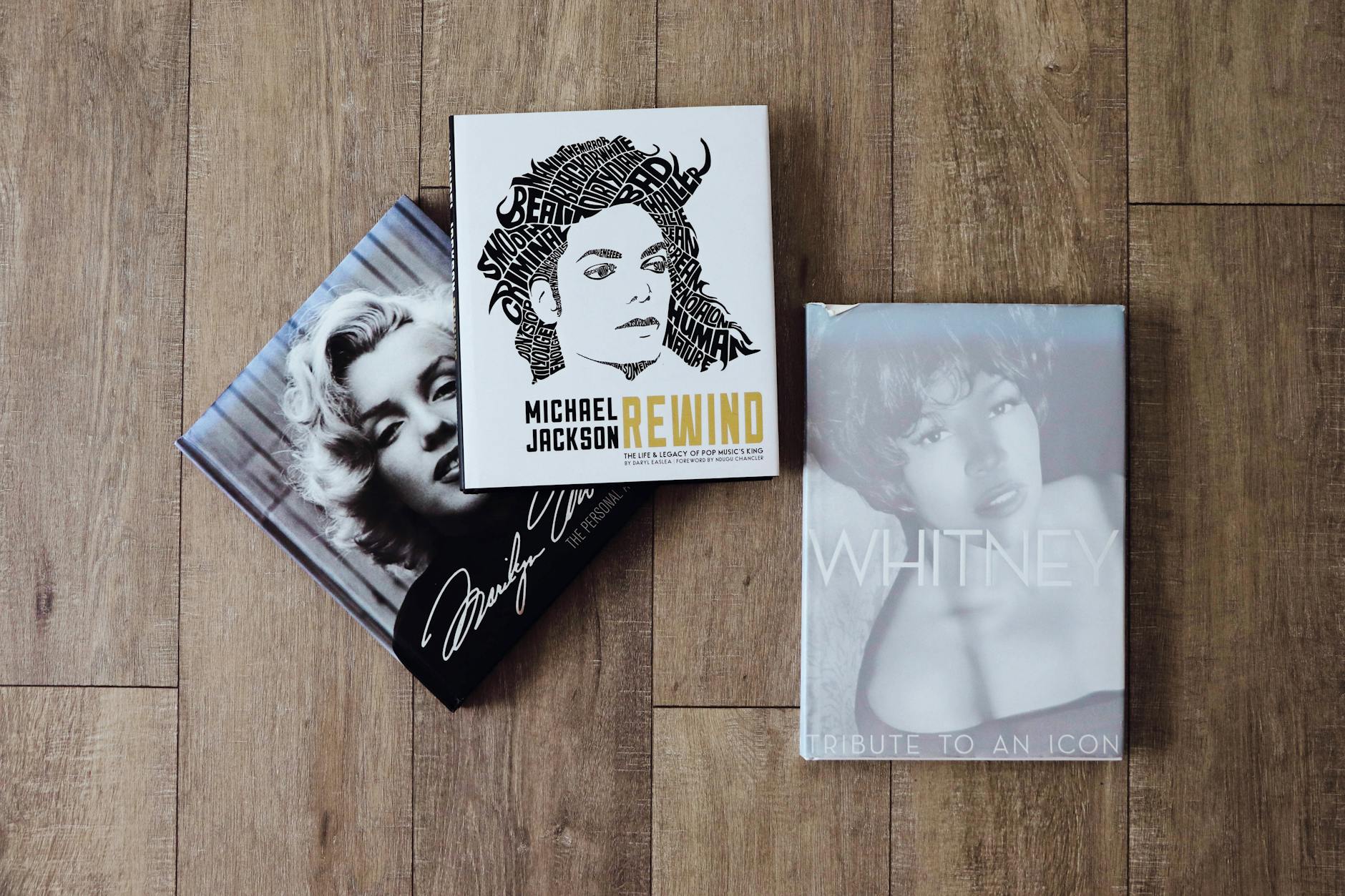 three books on a wooden floor with a photo of marilyn monroe