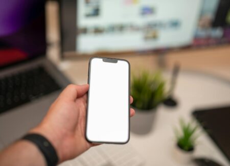 hand holding smartphone with blank screen in office