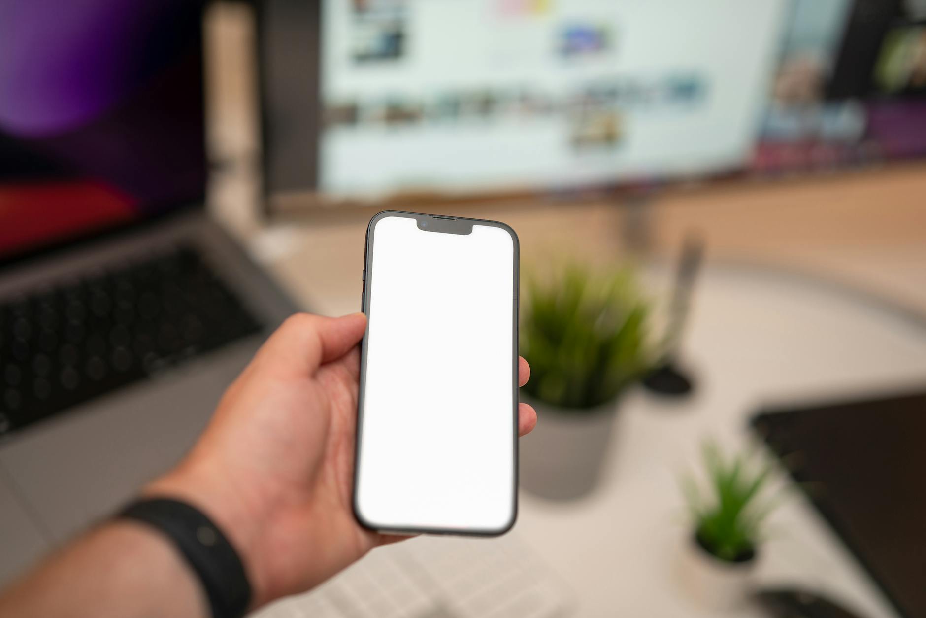 hand holding smartphone with blank screen in office